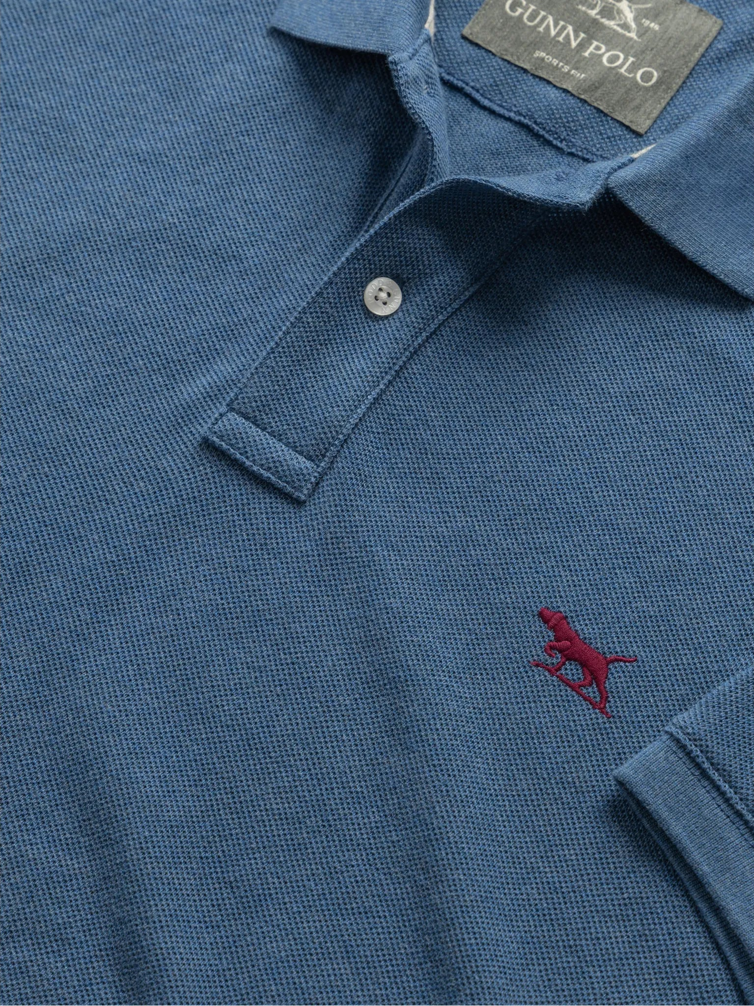 Blue polo shirt with a red logo and 'Gunn Polo' label on a white background